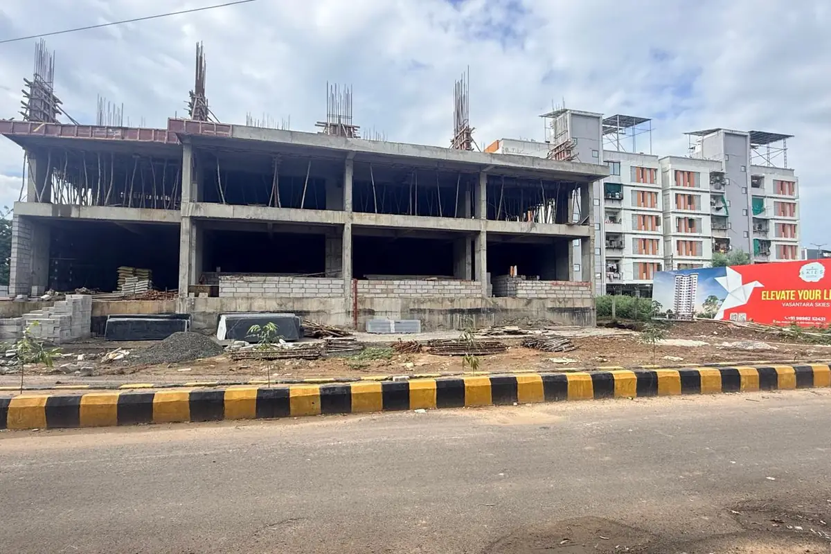 Vasantara Skies with ground and first floor slabs cast and upper columns rising, seen from the road